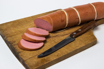Boiled sausage on a white background. Sliced sausage stick on a wooden board. Sausage product.