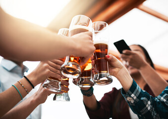 This is how we celebrate. Low angle shot of a group of young unrecognizable business colleagues having a celebratory toast with beer around a table.