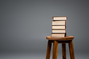 wooden stool with stack of books isolated on grey.