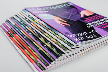 pile of beauty and style magazines on grey background, close up view.