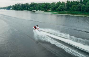 Aerial footage following a couple riding on a jet ski in the river