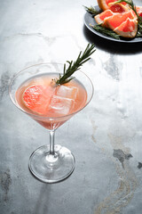 Grapefruit cocktail cocktail in a martini glass with rosemary, ice and grapefruit' slice. 