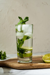 Non-alcoholic mojito with ice, mint and lime slices on wooden board. Refreshing summer cocktail.