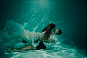Young couple kissing underwater on the bottom of the pool