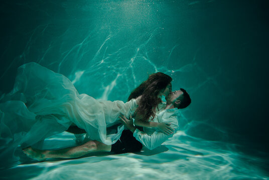 Young couple kissing underwater on the bottom of the pool - Powered by Adobe