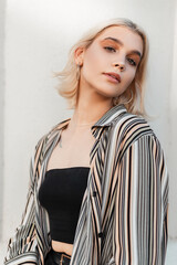 Beautiful young Caucasian girl with short blonde hair in fashion summer outfit on the street on a...