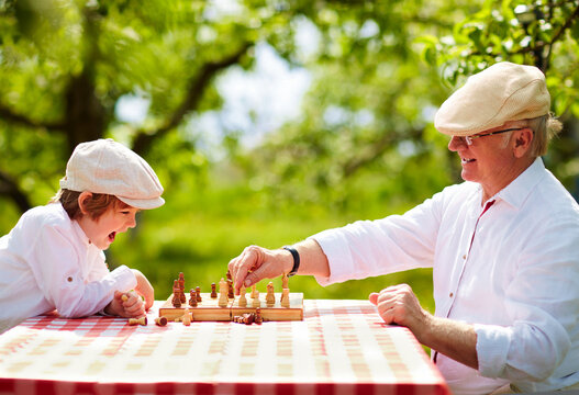 happy grandpa and grandson playing chess in spring garden
