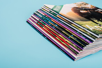 stack of colorful magazines collection isolated on blue.