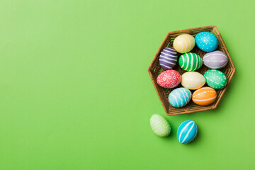 Multi colors Easter eggs in the woven basket on colored background . Pastel color Easter eggs. holiday concept with copy space