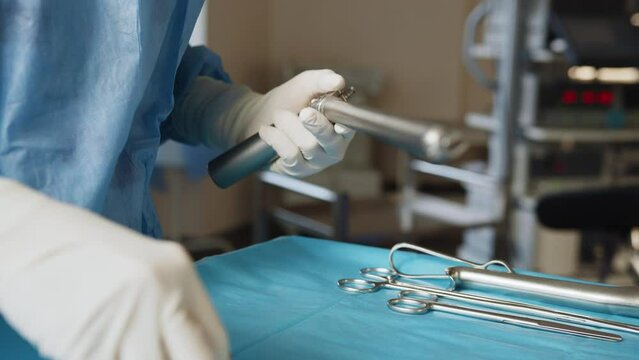 Surgical medical instruments on the table. Scrub nurse prepares medical instruments for surgery. Medical concept. Sterilized surgical instruments for laparoscopy with hand grabbing instrument.