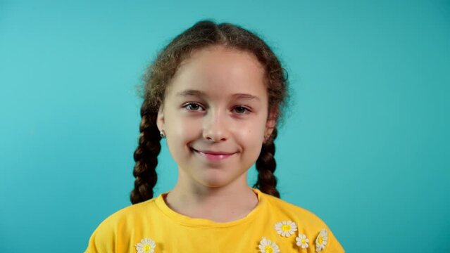Portrait of a happy child smiling, a little girl looking at the camera, smiling, a portrait of a child on a blue background, a cute child with a beautiful face. Happy childhood concept.