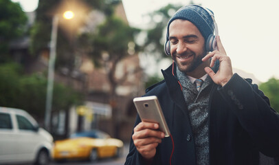 Music on....World off. Cropped shot of a fashionable young man listening to music on his phone while out in the city.