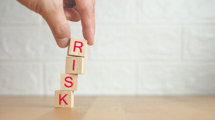 Risk management concept. Hand holding wooden cubes arranged creatively to describe the risk concept...