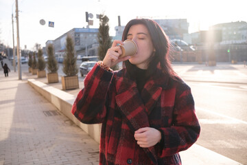 Fototapeta premium Woman drinking coffee in the sun, outdoor in sunlight light, enjoying her morning coffee.