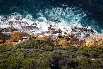 Aerial view of the wavy Tasmanian sea hitting the rocky cliffs on the coast