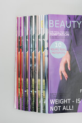 top view of beauty magazines stacked isolated on grey.