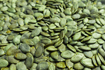 Background texture of green pumpkin seeds. Organic food, selective focus.