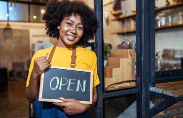 Young Female manager in restaurant with digital tablet or notebookWoman coffee shop owner with face mask hold open sign .Small business concept.