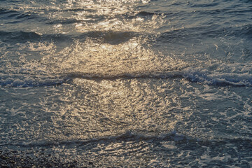 Horizontal lines of waves. Natural texture of sea water, illuminated by setting sun. Montenegro, Adriatic Sea