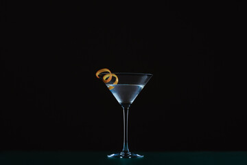Closeup of a martini in a cocktail glass served with orange peel isolated on a black background