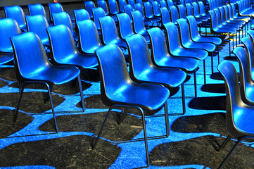 View of empty audience seats arranged in rows under the blue  flashlights