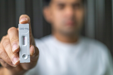 Young man are holding Rapid Antigen Test kit after swab COVID-19 test by himself at home and waiting for ATK examination and the result is negative. Self test, Home test. COVID-19 protection concept.