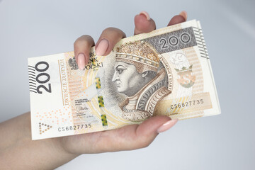 Polish currency held in the hand against a white background	
