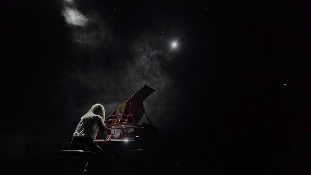 The pianist plays the piano in the backlight