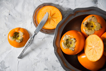 still life with persimmon on a gray cement background in a pewter dish, 