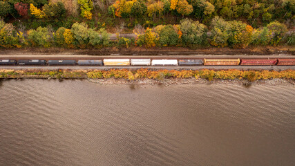Aerial view of the Hudson River with a train passing by surrounded by autumnal foliage