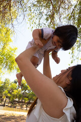 Young Hispanic mother playing with her one year old baby in a park