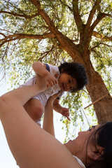 Young Hispanic mother playing with her one year old baby in a park