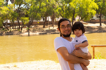 portrait of a Hispanic father and baby in a park smiling and having fun