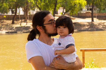 portrait of a Hispanic father and baby in a park smiling and having fun
