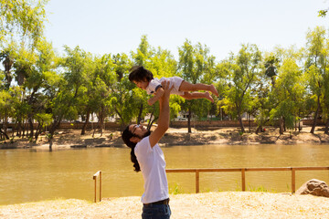 portrait of a Hispanic father and baby in a park smiling and having fun