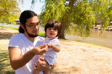 portrait of a Hispanic father and baby in a park smiling and having fun