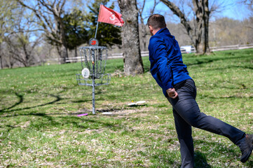 Disc golf player throwing a disc in the park.
