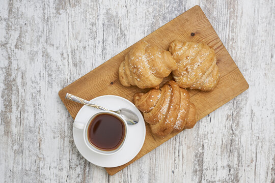 Top view shot of croissants and a coffee on a wooden board