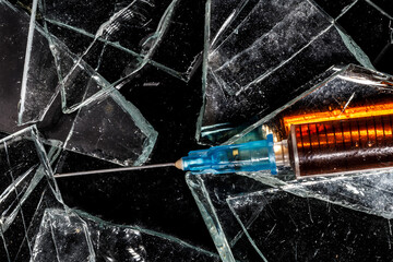medical syringe with drug close-up on broken glass