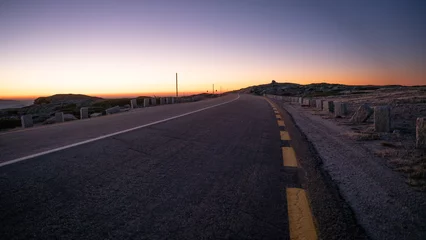 Foto auf Acrylglas Aubergine Nahaufnahme einer Straße mit Sonnenuntergang im Hintergrund