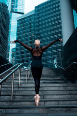 Ballerina, ballet dancer standing on stairs, on city street background © Elina Leonova