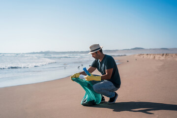 volunteer man collects plastic waste on the beach