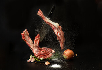 levitating cow ribs being seasoned with salt, on black background
