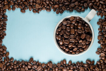 Many coffee beans in a traditional cup on blue background 