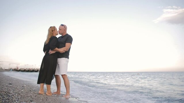 The son runs to the loving parents standing on the seashore. Happy hugs of a friendly family.