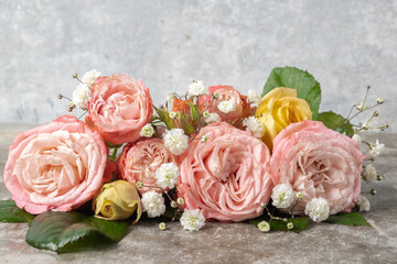 Closeup flower composition of yellow and pink roses on a gray concrete background.