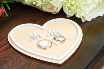The ring stand is made of wood, cozy and natural, with the inscription "Mr. and Mrs." close-up. The rings are fixed on the hearts not close.