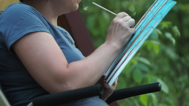 the artist sitting in nature draws with watercolor paints