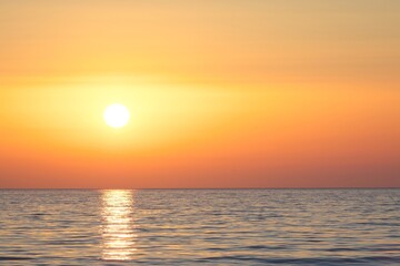 Calm sea in the evening. Hazy sun at sunset.