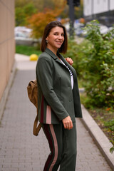 Portrait of a young business woman smiling on a background of a city outdoors. Model posing in a business suit and leather backpack